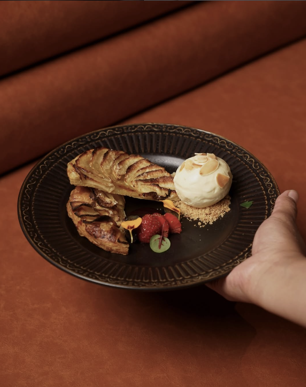 French apple tart with berries and almond-topped vanilla ice cream on a dark plate
